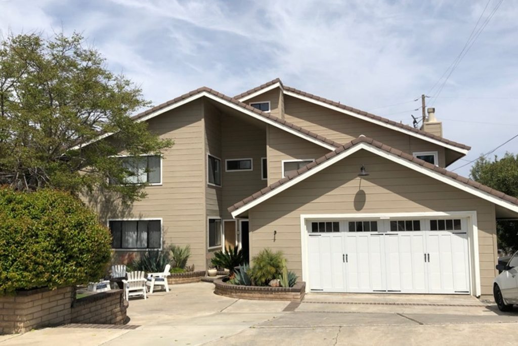 A two-story house with a white garage door and a landscaped front yard.